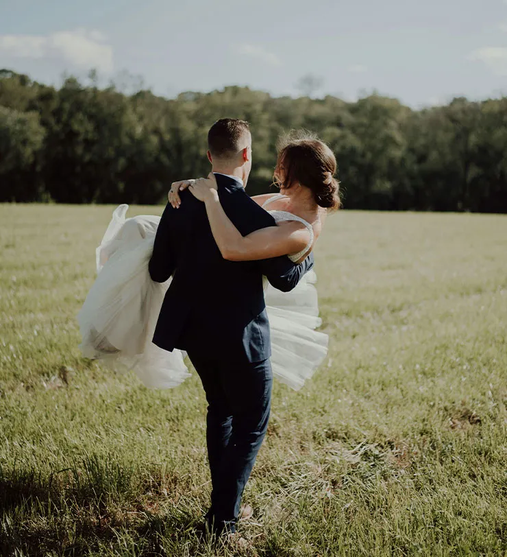 Marié portant sa femme en robe de mariée dans la nature, domaine de mariage Clos des Demoiselles